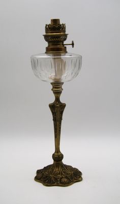 une lampe à huile ancienne en laiton et en verre sur fond blanc