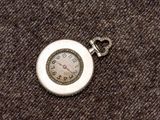 une montre de poche en argent posée sur un morceau de tissu