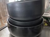 trois casseroles noires empilées les unes sur les autres sur une table