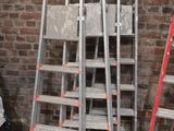 trois échelles appuyées contre un mur de briques