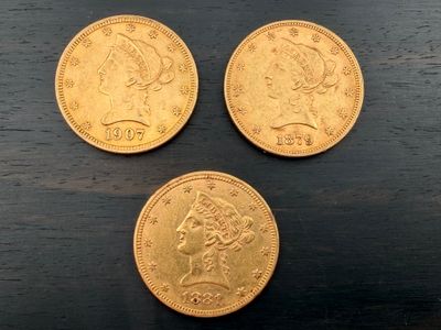 trois pièces d'or posées les unes à côté des autres sur une table