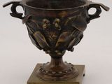 a bronze vase on a wooden stand on a white background