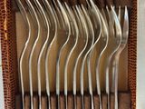 several forks and spoons in a leather case on a table