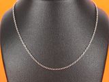 a silver necklace on a mannequin neck with an orange background
