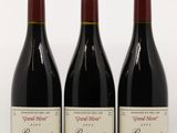 trois bouteilles de vin rouge sont alignées sur une surface blanche