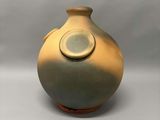 un vase marron avec un couvercle vert posé sur une surface blanche