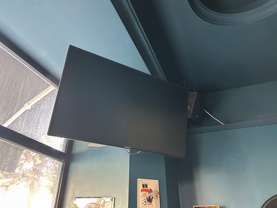 un téléviseur à écran plat suspendu au plafond dans une pièce
