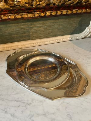 a silver plate that is on the floor next to a mirror