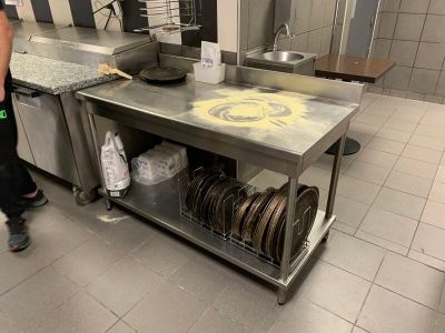 un homme debout dans une cuisine, près d'une table