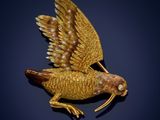 an image of a gold bird broochle on a black background