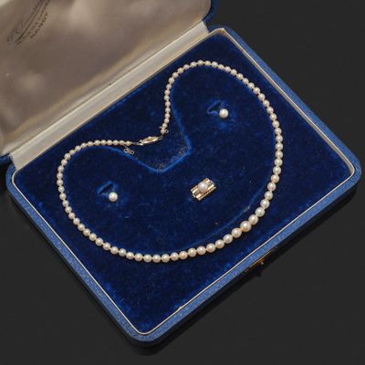 un collier de perles et une paire de boucles d'oreilles présentés dans un écrin en velours bleu