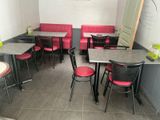 tables and chairs are lined up in a restaurant with red cushions