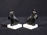 une paire de figurines de chiens noirs sur des socles en marbre, sur fond noir