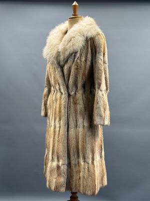 a fur coat on a mannequin stand against a gray background