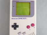 an old game boy with a green screen sitting on top of a table