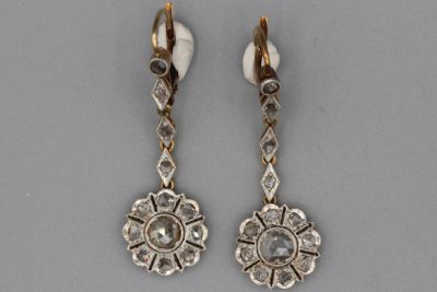 deux paires de boucles d'oreilles ornées de diamants, posées sur un fond gris