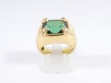 a close up of a gold ring with a green stone