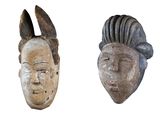 two wooden masks are shown on a white background, one of which has a man ' s face and the other of which is a woman ' s face