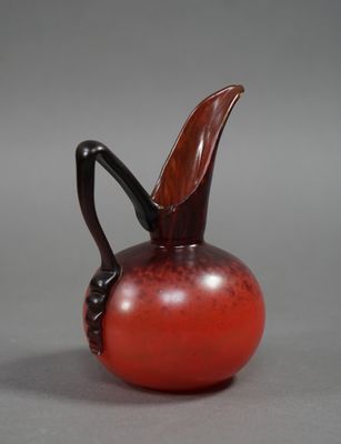 une image représentant un vase en verre rouge muni d'une anse noire