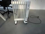 a white radiator sitting on the floor next to a black chair