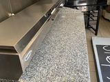stainless steel counter top in a commercial kitchen with a pizza oven in the background
