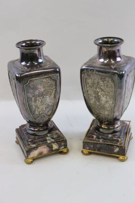 two silver vases sitting on top of each other