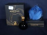 une image représentant un flacon de parfum à côté d'une boîte ornée d'une plume bleue
