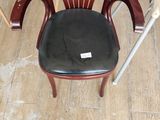 a wooden chair with a black seat in the middle of a room