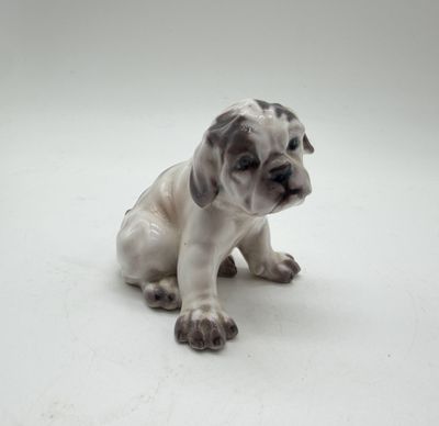 a figurine of a dog sitting on a white surface