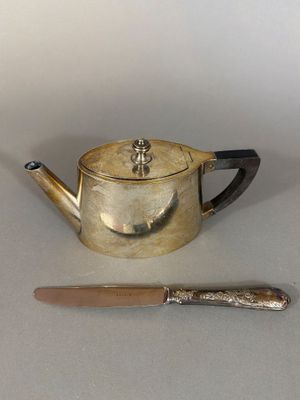 a silver tea pot and a knife on a table