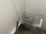 une chaise en plastique transparent près d'un mur, avec un chat dans un bol