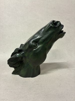 une sculpture verte représentant la tête d'un chien, la gueule ouverte