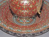 a red and gold tea pot on a saucer