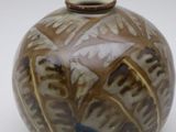 a brown and blue vase sitting on a white surface