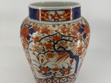 an orange and blue vase with a bird and flowers on it