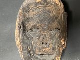 an old wooden mask on a table with a tag on it