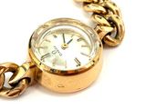 a gold watch with a chain around it on a white surface