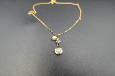 un collier en or avec un pendentif en perle au bout d'une chaîne