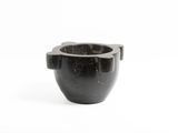 une tasse en marbre noir munie d'une anse, sur fond blanc