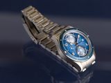 a silver watch with a blue face on a blue surface