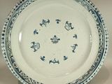une assiette bleue et blanche posée sur un support, sur une table