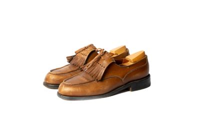 chaussures en cuir beige ornées de pompons sur fond blanc