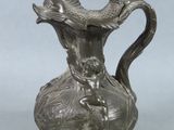 a silver vase with a fish on it on a table