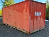 a red container sitting in the middle of a gravel lot