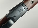 a close up of a rifle with a wooden handle on a white surface