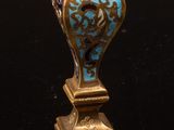 un vase bleu et or posé sur une surface noire