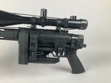 the rifle is sitting on a white surface with a scope on top of it