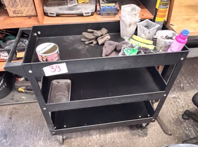 a black work cart with tools on it in a garage