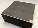 a black box with a gold trim sitting on a white surface