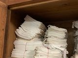 plusieurs piles de serviettes blanches pliées, posées sur une étagère en bois dans un placard